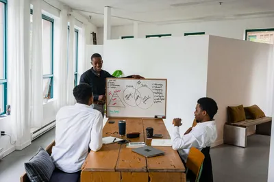 Three people in a strategy meeting working through tradeoffs at a whiteboard